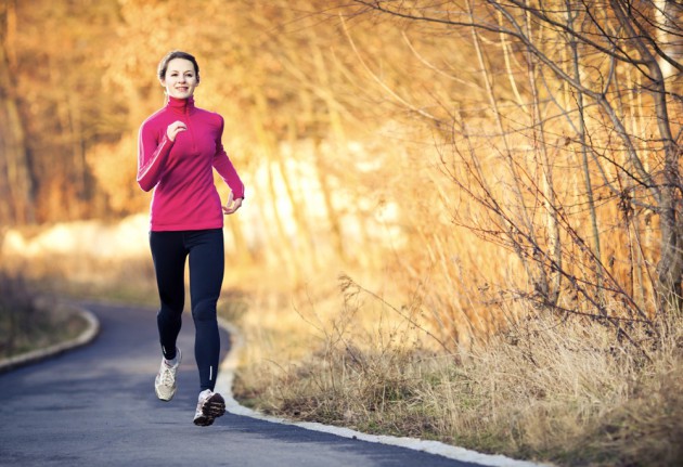 Young woman running outdoors in a city park on a cold fall-winter day (motion blurred image)